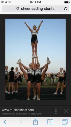 a group of cheerleaders standing on top of each other with their hands in the air