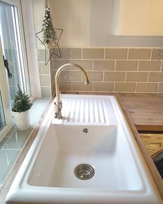 a white sink sitting under a window next to a wooden counter top in a kitchen