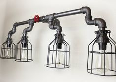 three light fixtures are attached to the wall with pipes and caged lights on them