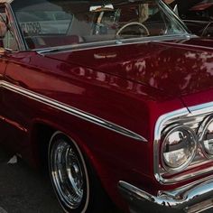 an old red car parked in a parking lot