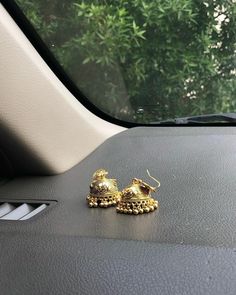 two gold bells sitting on the dashboard of a car