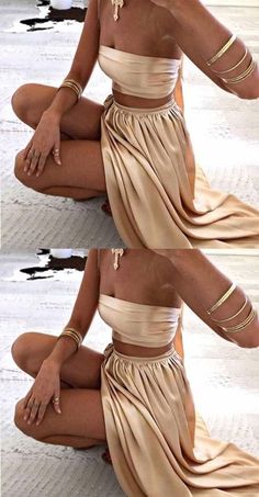 a woman sitting on the ground wearing a tan skirt and matching top with gold bracelets