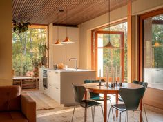 a kitchen and dining room with wood floors, windows, and wooden ceilinging is shown in this image