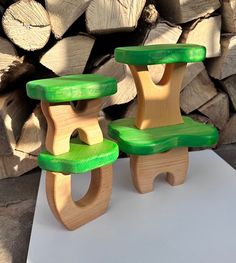 two wooden chairs sitting next to each other on top of a white table with logs in the background