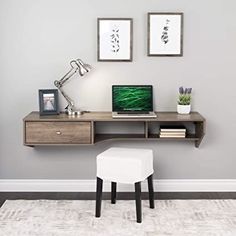 a desk with a laptop on top of it and two pictures hanging above the desk