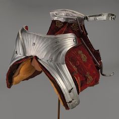 a helmet on a wooden stick with metal fittings and red fabric covering the back