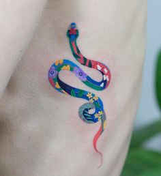 a colorful snake tattoo on the side of a woman's stomach