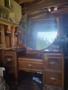 an old vanity with a large round mirror on it's top and drawers below