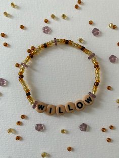 a beaded bracelet with the word willow spelled in small letters on it, surrounded by tiny beads