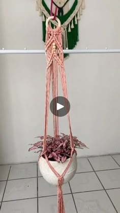 a potted plant hanging from a hook on a tiled floor next to a wall