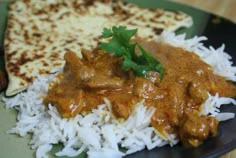 a green plate topped with rice and meat covered in gravy