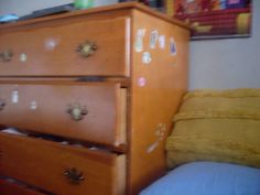 a wooden dresser sitting next to a yellow pillow