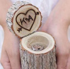 two hands holding a piece of wood that has been carved into the shape of a heart