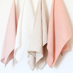 three pink and white towels hanging on the wall