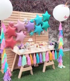 a table topped with balloons and tassels next to a wooden wall covered in stars