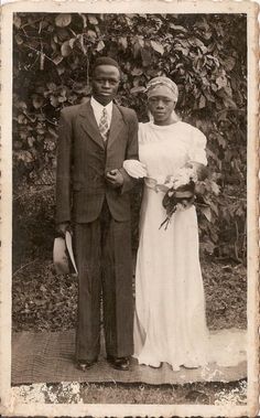 an old black and white photo of a man and woman in formal wear standing next to each other