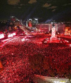 a large group of people standing in the middle of a street with red lights on them