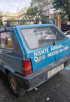 an old blue car parked on the side of the road