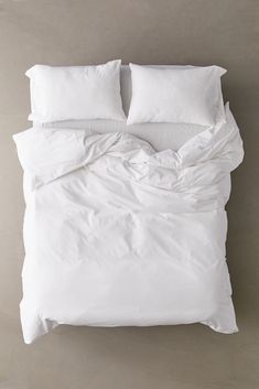 an unmade bed with white sheets and pillows