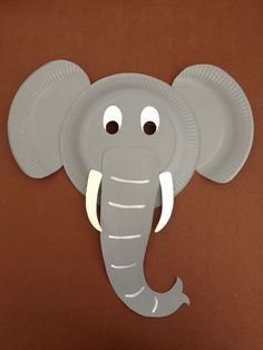 a paper plate elephant with eyes on it's head is hanging on the wall