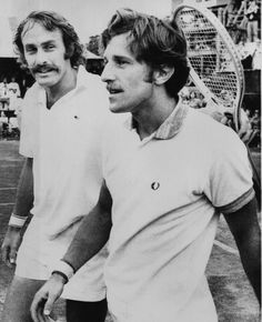 two men standing next to each other holding tennis racquets