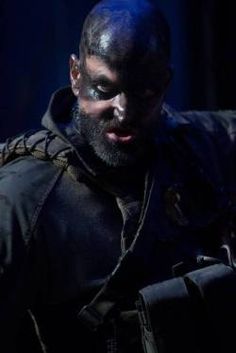 a man with black paint on his face and beard is looking down at something in the dark