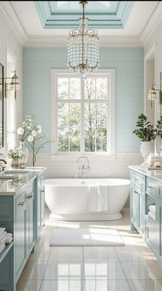 a white bath tub sitting under a window next to a chandelier in a bathroom