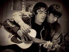 two young men are playing the guitar together