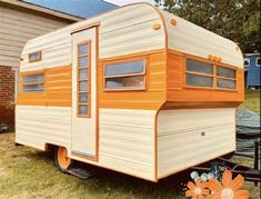 an orange and white trailer parked in front of a house