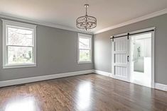 an empty living room with hard wood floors and white trim on the doors, windows, and french doors