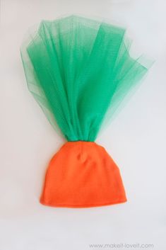 an orange and green mesh bag with a carrot in it's center on a white surface