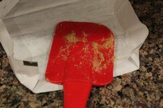 a red spatula sitting on top of a piece of paper next to a white bag