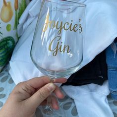 a person holding up a wine glass with the words joyce's gin on it