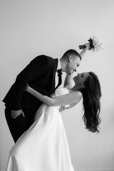 a bride and groom are posing for a photo in black and white with their arms around each other