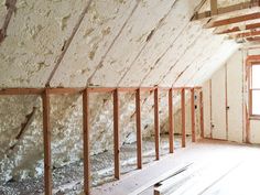 an unfinished room with exposed walls and wooden beams on the ceiling, in front of a window