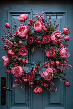 a blue door with a pink wreath and flowers hanging on it's front door