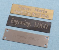 three metal name tags sitting on top of a blue surface