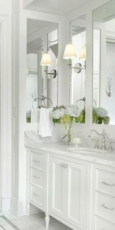 a white bathroom with two sinks and mirrors