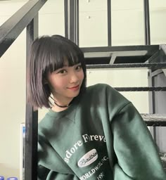 a young woman sitting in front of a metal rack