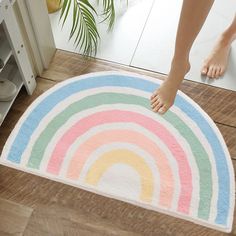 a person standing on the floor in front of a bath mat with a rainbow design