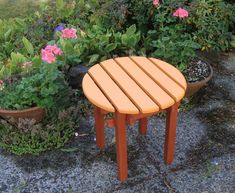 an orange wooden table sitting in front of some potted plants and flowers on the ground