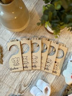 four wooden baby name tags sitting on top of a table next to a potted plant