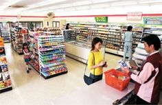 two people standing at the cash register in a grocery store