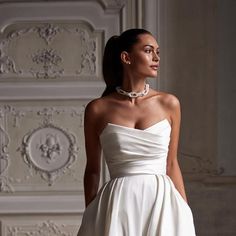 a woman in a strapless white dress stands with her back turned to the camera