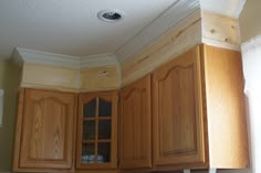 an empty kitchen with wooden cabinets and white trim on the wall above the stove top