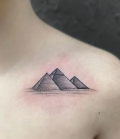 a woman's chest with three pyramids tattoo on her left shoulder and right arm