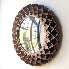 a round mirror mounted to the side of a wall next to a white wall with a window