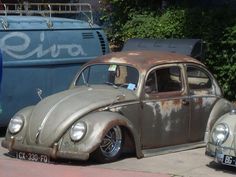 an old vw bug is parked on the side of the road next to another car