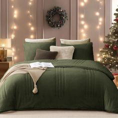 a bed with green comforter and christmas lights