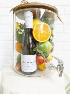 a bottle of wine sitting on top of a table filled with fruit